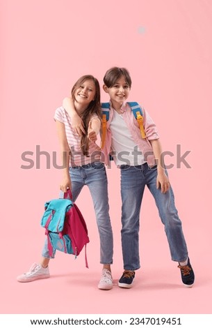 Little pupils with backpacks hugging on pink background