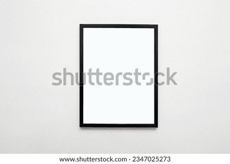 black picture frame on white wall. Stylish modern photoframe for poster or picture