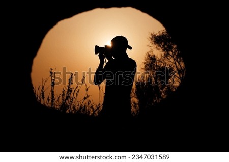 Photographer taking a nature photo during sunset. Picture taken from the hole of a cave