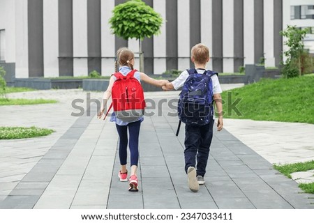Boy and girl with backpack behind back. Back to school. Children go to school for study. Beginning of school lessons. Concept of school, study, education, friendship, childhood Royalty-Free Stock Photo #2347033411