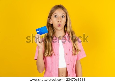 Photo of beautiful caucasian kid girl wearing pink jacket amazed shocked hold credit card payment