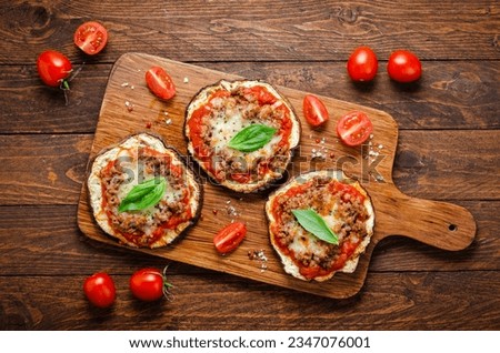 Eggplant Pizza with Tomato Sauce, Minced Meat, Mozzarella and Basil, Mini Pizza over Rustic Background Royalty-Free Stock Photo #2347076001