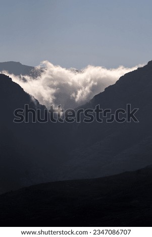 Cloud bank peaking through a dark valley in the early morning sunlight