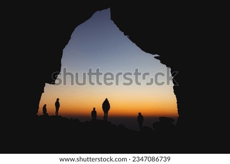 silhouette of a group of hikers standing in the wolf berg arch with the sunrise in  the background