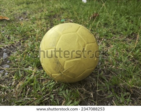 a picture of a yellow football made of plastic, against a green grass background
