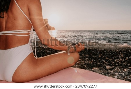 Woman sea yoga. Happy woman in white swimsuit and boho style braclets practicing outdoors on yoga mat by sea on sunset. Women yoga fitness routine. Healthy lifestyle, harmony and meditation
