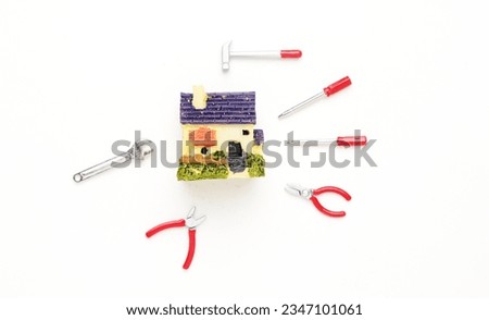 A picture of house miniature with repairing tools on white background. House maintainence concept.