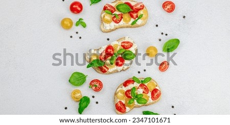 Fresh bread sandwiches with tomato cherry, cream cheese and basil leaves. Morning breakfast concept. Hard light, dark shadow, white stone concrete background, banner format Royalty-Free Stock Photo #2347101671