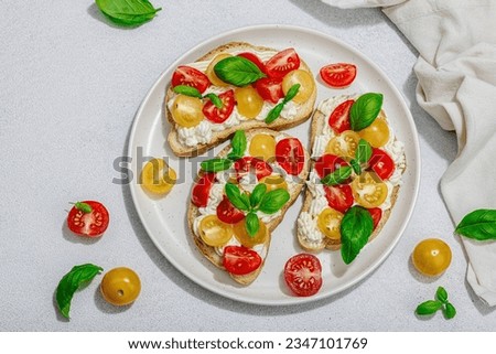 Fresh bread sandwiches with tomato cherry, cream cheese and basil leaves. Morning breakfast concept. Hard light, dark shadow, white stone concrete background, top view Royalty-Free Stock Photo #2347101769