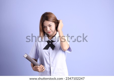 The Asian girl in Thai student uniform standing on the purple background.