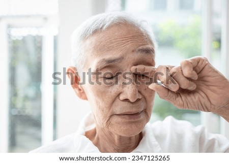 Old elderly rubbing her eye,dry eyes,irritation,redness and itching,senior suffer from senile cataract,eye-related diseases,blurred clouded vision or double vision,sensitive to bright lights and glare Royalty-Free Stock Photo #2347125265