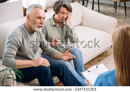Anxious mature couple sitting on couch, listening doctor explaining prescription, test results, diagnosis, treatment plan. Private clinic or home visit, modern healthcare concept