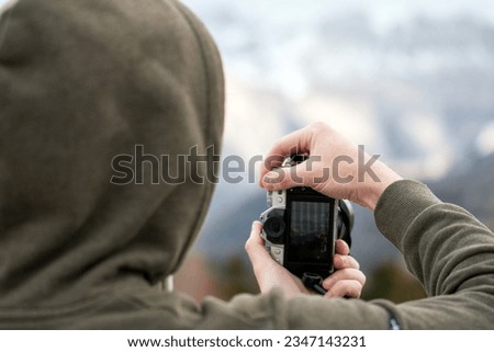 Amateur Photographer Capturing Mountain Moments with Modern Camera. Screen visible. Camera LCD screen as a viewfinder