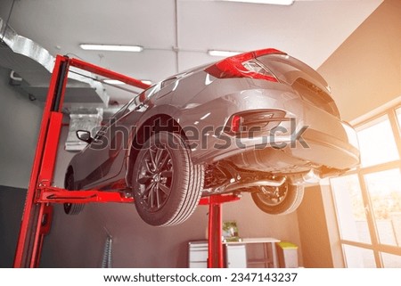 The car is being lifted up by a hydraulic machine for a technician. Close-up modern japanese car. Royalty-Free Stock Photo #2347143237