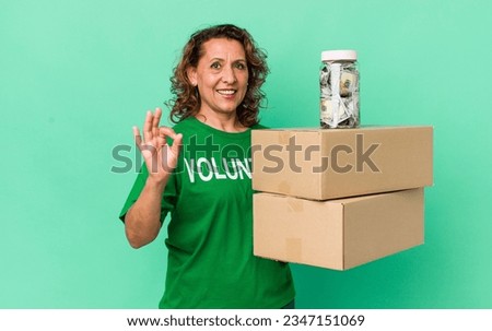 middle age woman feeling happy, showing approval with okay gesture. volunteer and donation concept