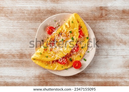 An omelet with tomato and parsley, eggs for breakfast, a healthy vegetarian omelette with cheese, overhead flat lay shot on a rustic wooden background Royalty-Free Stock Photo #2347155095