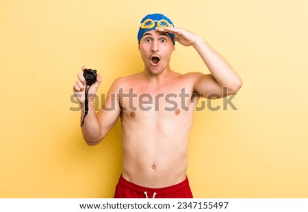 young handsome guy looking happy, astonished and surprised. swimmer concept