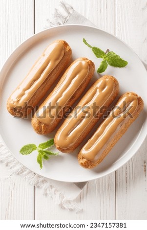 Traditional french eclairs filled with coffee cream close-up in a plate on the table. Vertical top view from above
 Royalty-Free Stock Photo #2347157381