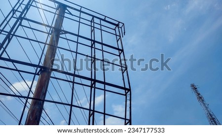 The rusty billboard frame stands by the road against the blue sky