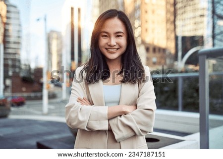 Happy young confident Asian business woman professional office worker, businesswoman executive manager wearing suit standing arms crossed outdoors on big city street looking at camera, portrait. Royalty-Free Stock Photo #2347187151
