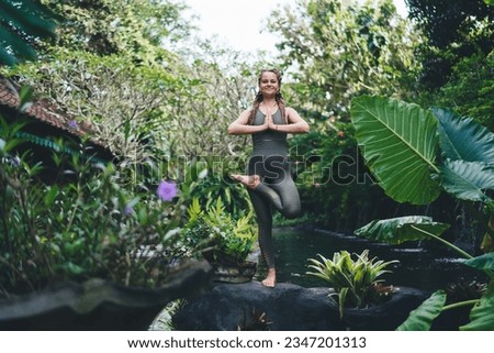 Barefoot female yogi in spandex tracksuit practice hatha sport at Bali keeping healthy lifestyle, Caucasian smiling woman in flexible yoga pose meditating for feeling harmony peace and bliss Royalty-Free Stock Photo #2347201313