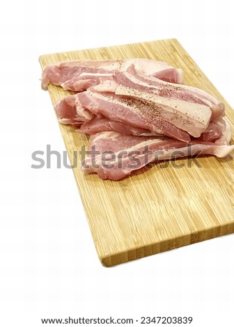 a photography of bacon on a cutting board with a knife, meat cleavers on a cutting board on a white background.