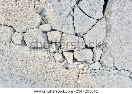 a photography of a crack in the concrete wall with a small piece of rock, stone wall with cracks and cracks in it.
