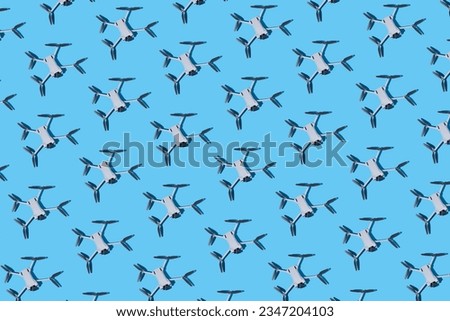Pattern of gray drones, with photo and video cameras, and dark propellers on a blue background. UAV, fly, spy, altitude, unmanned, technology and futuristic concept.