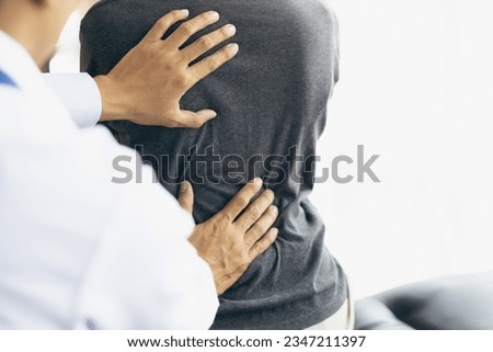 Doctor examining woman back pain in examination room. Doctor practicing back and shoulder physiotherapy for female patient in hospital. Royalty-Free Stock Photo #2347211397