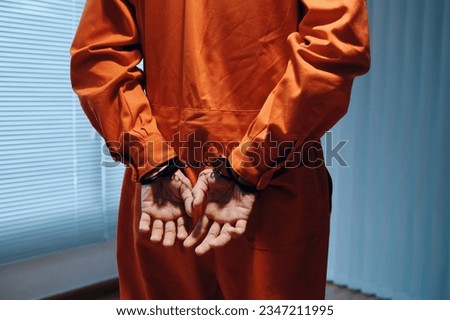 Arrested criminal with handcuffs waiting for detective in interrogation room Royalty-Free Stock Photo #2347211995