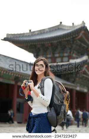 A young foreign woman holding a camera and taking pictures during a trip to Korea