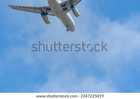 Overhead view of a commercial jet airliner flying into the picture frame as it prepares for a landing with its wheels down 