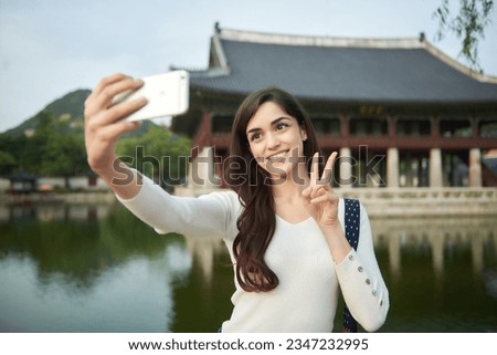  A young foreign woman holding a camera and taking pictures during a trip to Korea