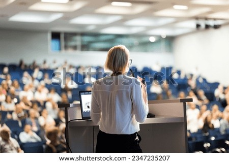 Female speaker giving a talk on corporate business conference. Unrecognizable people in audience at conference hall. Business and Entrepreneurship event Royalty-Free Stock Photo #2347235207