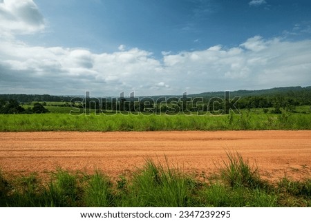 Side view of gravel road in countryside with meadow. Royalty-Free Stock Photo #2347239295