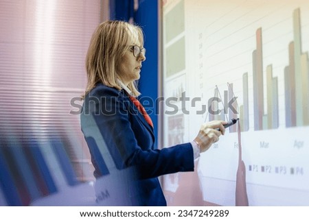 Well-dressed professor giving a lecture to her students about graphs and charts Royalty-Free Stock Photo #2347249289
