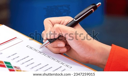 A safety engineer is using pen to rating the health risk assessment level of chemical hazardous material in the paperwork form. Industrial safety working scene, close-up and selecitve focus. Royalty-Free Stock Photo #2347259015