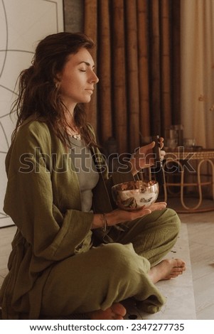 Woman playing on Tibetan singing bowl while sitting on yoga mat. Vintage tonned. Soft focus blurred and noise effect. Royalty-Free Stock Photo #2347277735