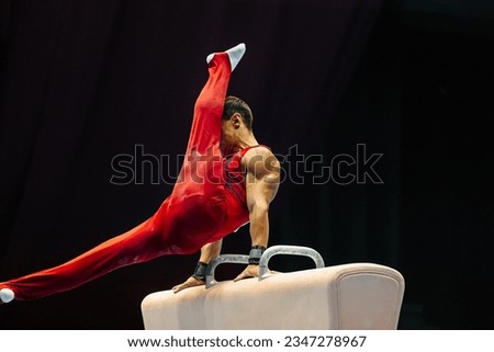 gymnast exercise pommel horse in championship gymnastics, support with hands on horse, swing feet