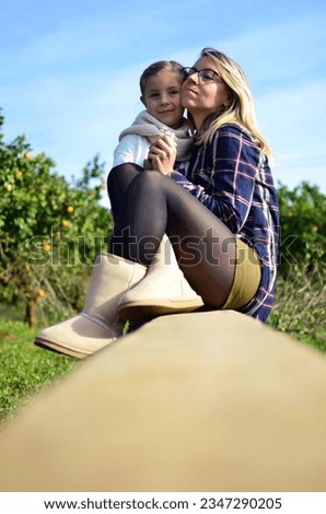 Autumn portrait of mother and daughter hugging among orange trees