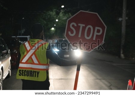 Security guard holding stop slow down sign at night construction site in Toronto