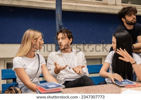 Three colleagues discussing at table during break at college. Male student explaining and gesticulating Royalty-Free Stock Photo #2347307773