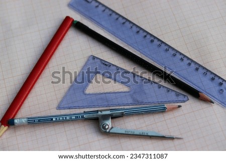 Pencil, ruler, triangle, compass on graph paper background