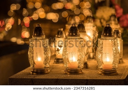 Candle lights on graves and tombstones at a cemetery in Poland during All Saints Day, Zaduszki day, and Day of the Dead. Lit candles illuminate the graves at a Christian cemetery at night. Royalty-Free Stock Photo #2347316281