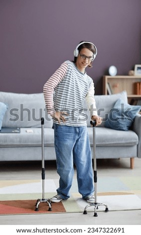 Vertical full length portrait of smiling teenage girl with cerebral palsy wearing headphones at home and posing Royalty-Free Stock Photo #2347322691