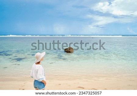 Vacation on the seashore. Young woman on the beautiful tropical white sand beach.