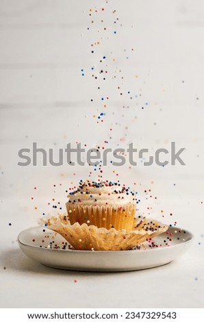 Vanilla cupcakes, white background, simple, elegant desserts. Falling sprinkles. Bright and fun. Cute baked goods. Restaurant images. Bakery foods. Professional photos 