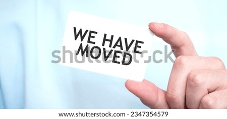 Man in blue sweatshirt holding a card with text WE HAVE MOVED, business concept