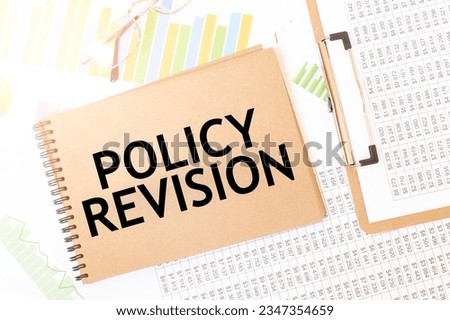 Business up graph on a sheet of craft colour Notepad with policy revision sign. Notepad on desk with financial documentation