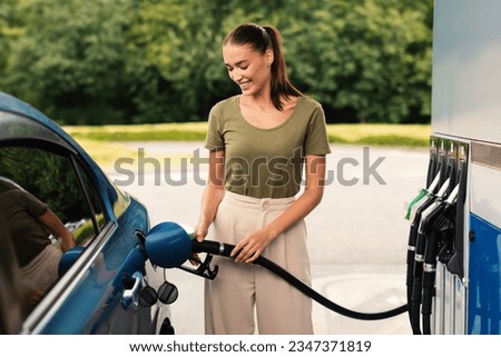 Smiling Woman Refilling Auto with Bio Fuel at Modern Petrol Station Outdoor, Enjoying Refueling Experience. Eco Friendly and Convenient Car Care, Automobile Fueling Offer Concept Royalty-Free Stock Photo #2347371819